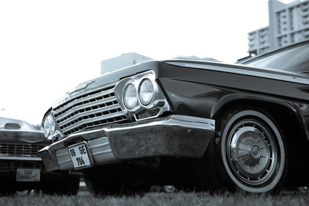 Vintage Chevrolet Impala displayed at an urban car exhibition with distinctive chrome details.